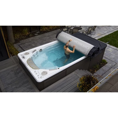 Feltekerhető Hydropool termotető használat közben: egy személy részben feltekeri a fedést egy úszómedencén.